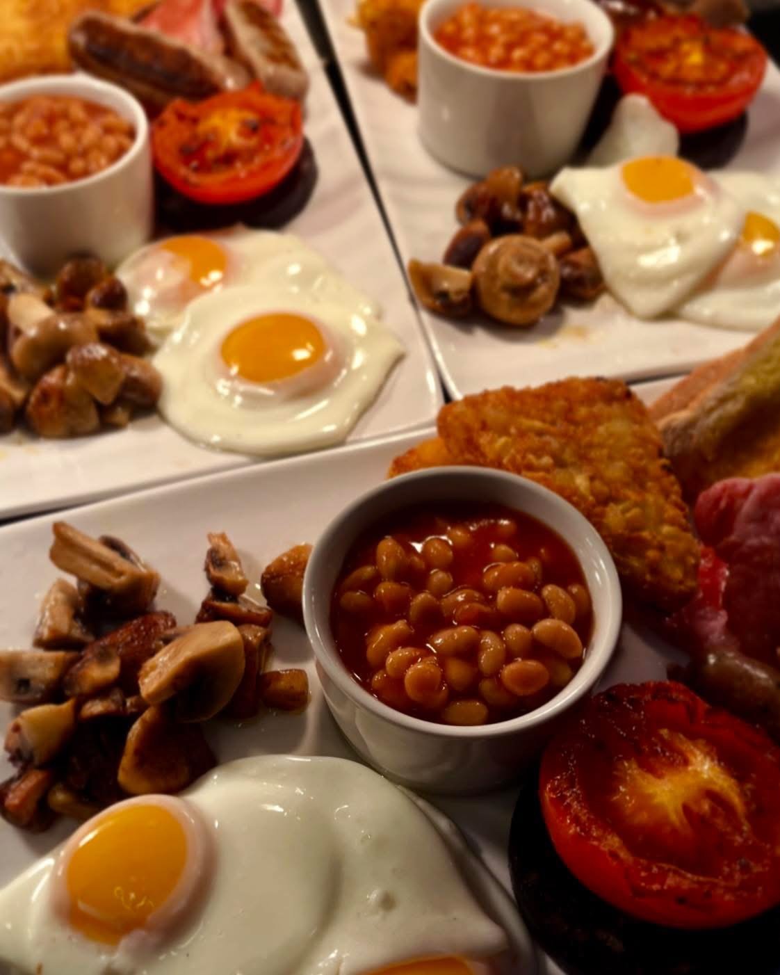 Multiple full English breakfast plates prepared together for a group booking
