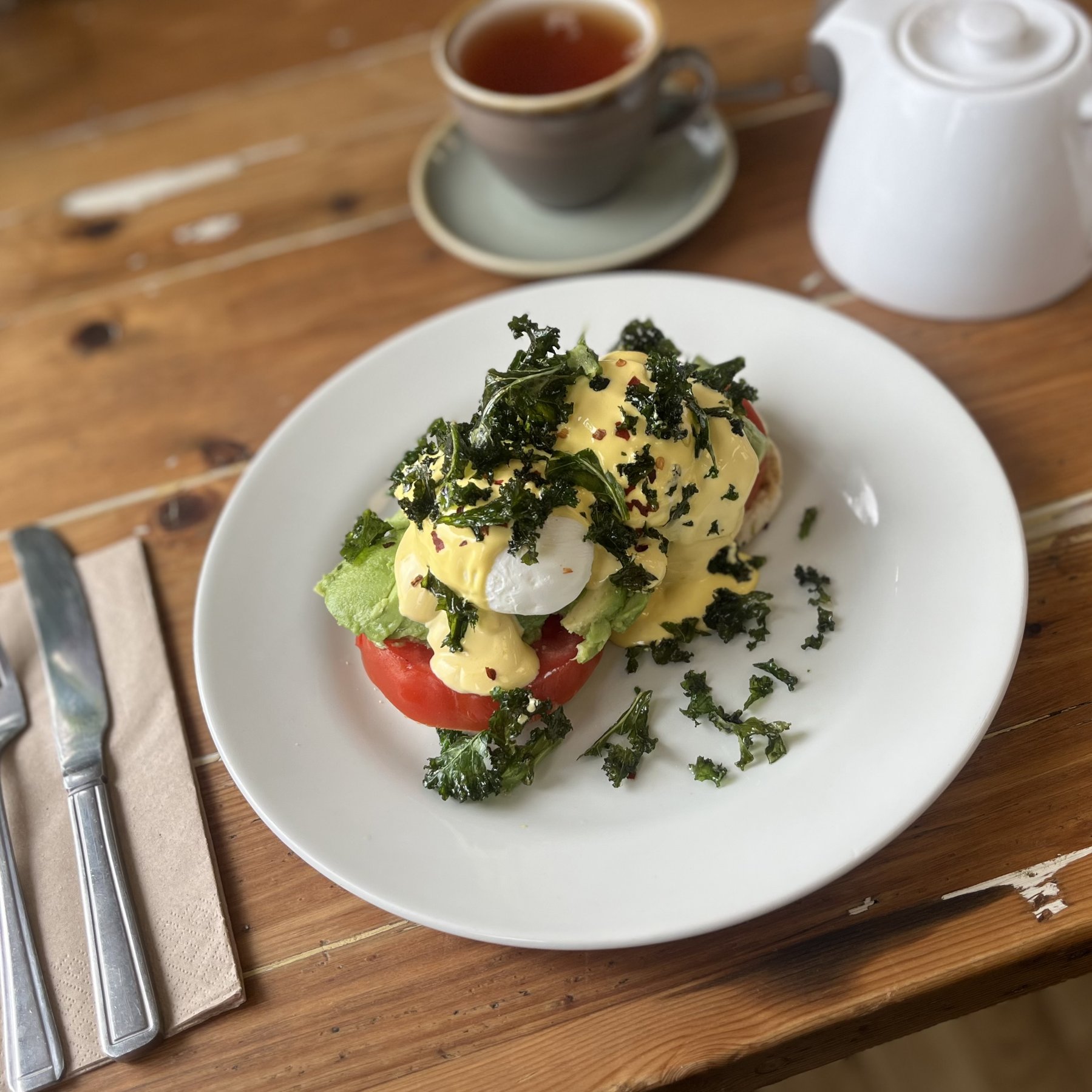 Eggs benedict with kale and hollandaise, served with a pot of tea