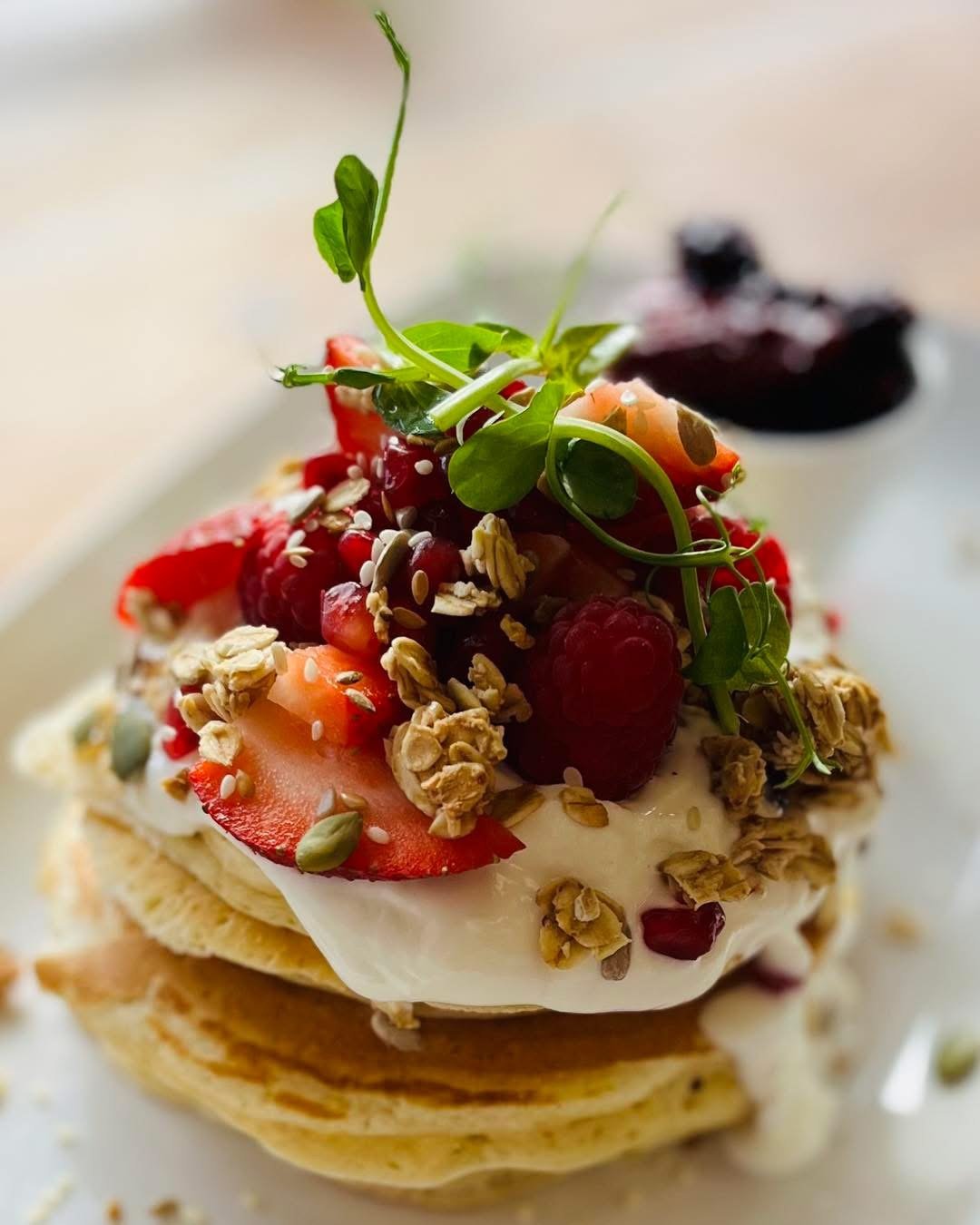 A stack of pancakes with berries and granola