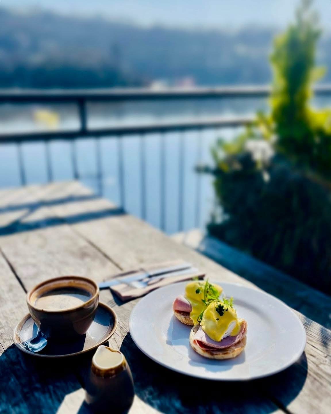 Eggs benedict and coffee on the balcony with the lake and hills behind