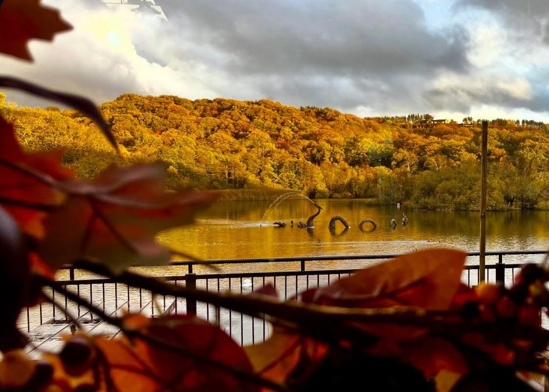 The lake and fountain sculpture seen through autumn leaves