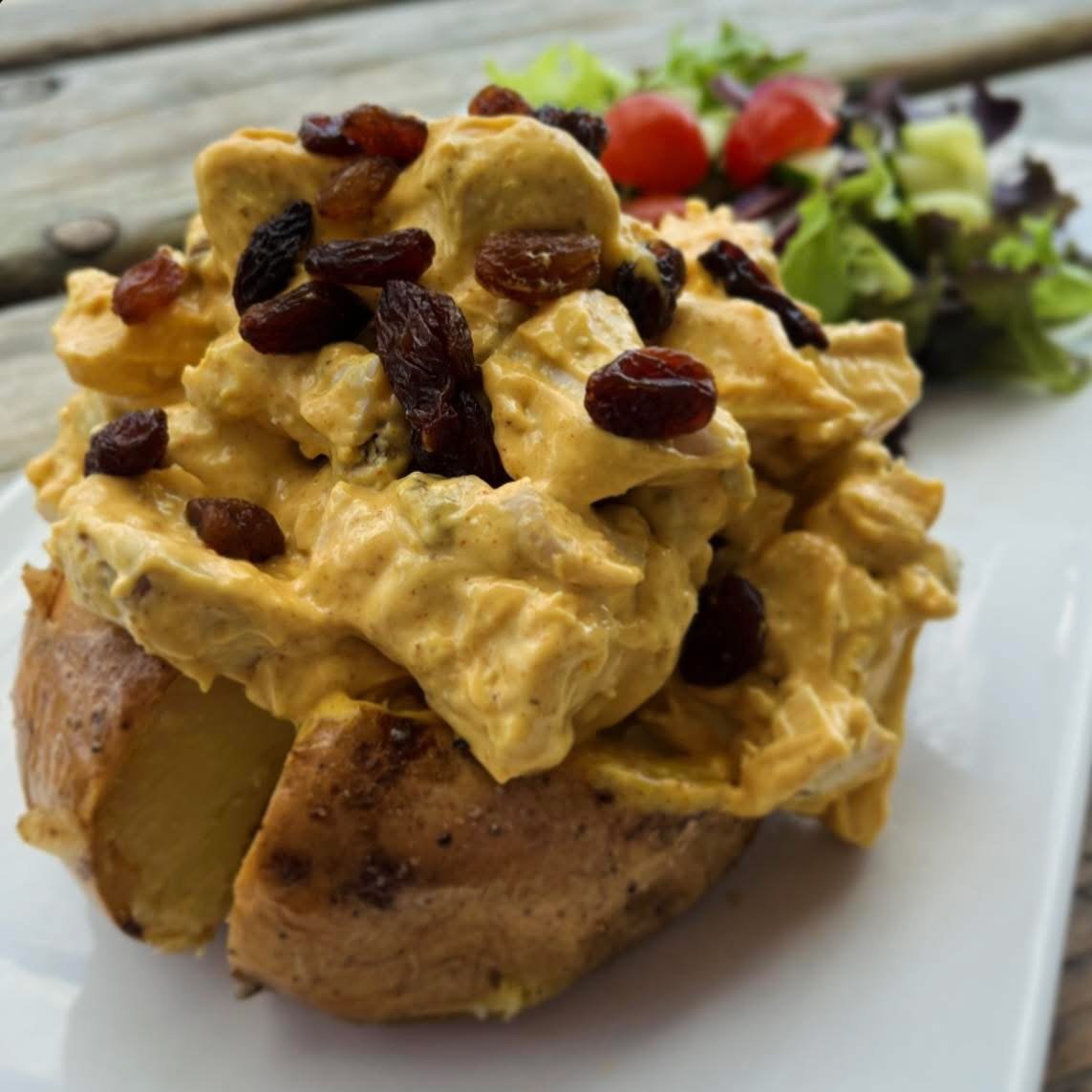 A baked potato topped with curried chicken salad