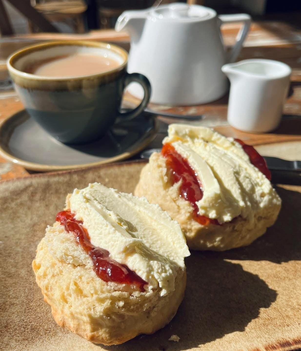 A cream tea with two scones, jam, cream and a pot of tea